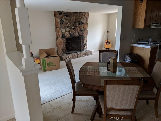 49438 Conejo Rd, Morongo Valley, CA 92256 - dining area with light tile patterned floors, a stone fireplace, and light colored carpet