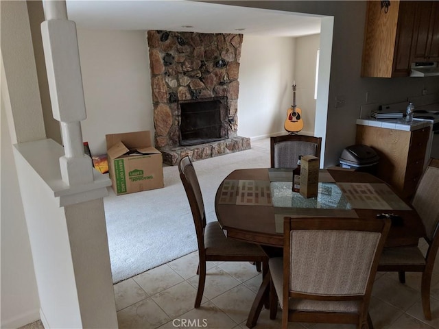 49438 Conejo Rd, Morongo Valley, CA 92256 - dining area with light tile patterned floors, a stone fireplace, and light colored carpet