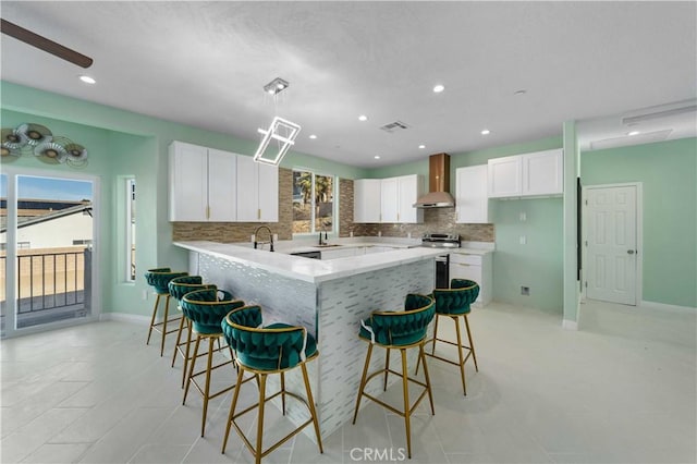 18189 Kalin Ranch Dr, Victorville, CA 92395 - kitchen featuring wall chimney exhaust hood, backsplash, a kitchen breakfast bar, white cabinets, and recessed lighting