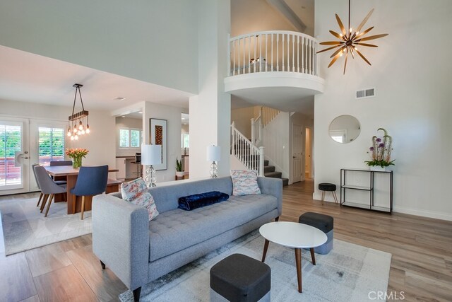 7411 Brava St, Carlsbad, CA 92009 - living area with stairs, light wood-type flooring, a towering ceiling, a chandelier, and baseboards