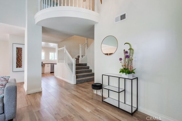 7411 Brava St, Carlsbad, CA 92009 - entryway with light wood-style flooring, stairway, a high ceiling, and baseboards