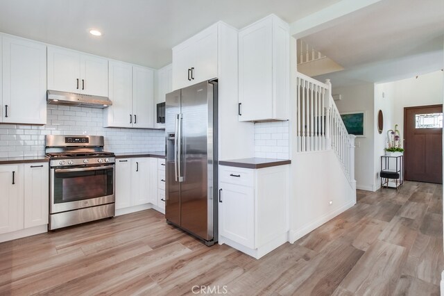 7411 Brava St, Carlsbad, CA 92009 - kitchen with stainless steel appliances, under cabinet range hood, dark countertops, light wood-type flooring, and recessed lighting