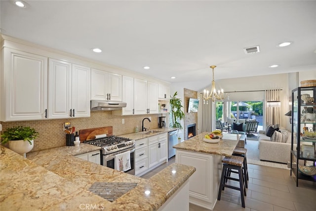 6617 Oak Forest Dr, Oak Park, CA 91377 - kitchen with appliances with stainless steel finishes, under cabinet range hood, decorative backsplash, a sink, and light stone countertops