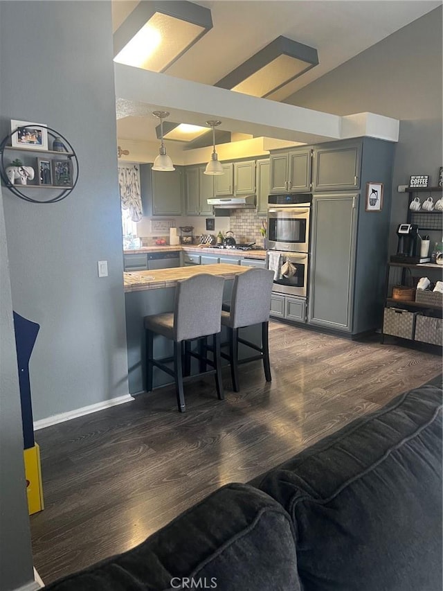 11420 Lasselle St, Moreno Valley, CA 92557 - kitchen with stainless steel appliances, dark wood finished floors, light countertops, decorative backsplash, and hanging light fixtures