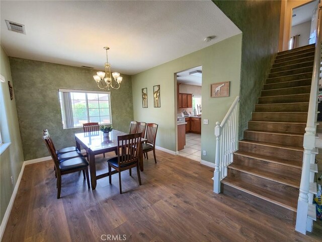 43620 Brahea Ct, Indio, CA 92201 - dining space with dark wood-type flooring, stairway, a chandelier, and baseboards