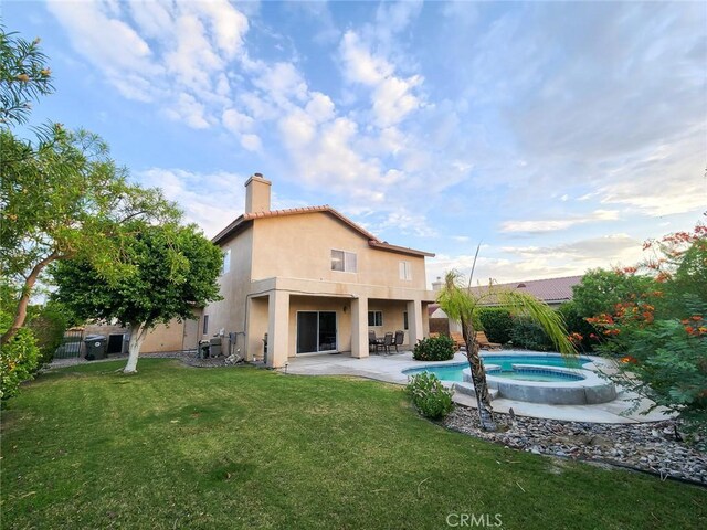 43620 Brahea Ct, Indio, CA 92201 - rear view of house with stucco siding, an in-ground hot tub, a chimney, and a patio area