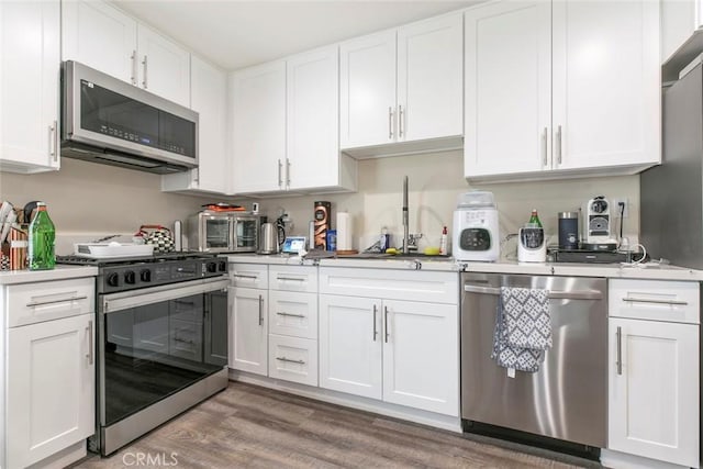 17465 Tuscan Dr, Granada Hills, CA 91344 - kitchen featuring stainless steel appliances, a sink, light wood-type flooring, white cabinets, and light countertops