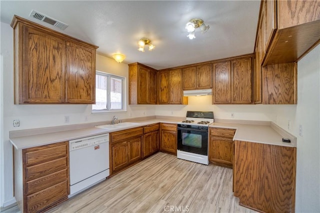 502 Robert Ct, Nipomo, CA 93444 - kitchen featuring range with gas cooktop, white dishwasher, under cabinet range hood, brown cabinetry, and light wood-style flooring