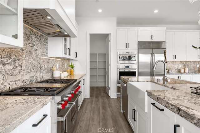 59 Longchamp, Irvine, CA 92602 - kitchen featuring high quality appliances, wall chimney exhaust hood, a sink, glass insert cabinets, and white cabinets