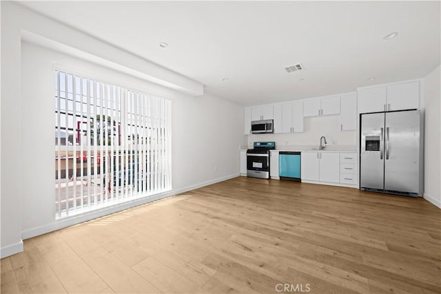 5218 Auckland Ave, Toluca Lake, CA 91601 - kitchen with stainless steel appliances, a sink, light wood finished floors, baseboards, and white cabinets