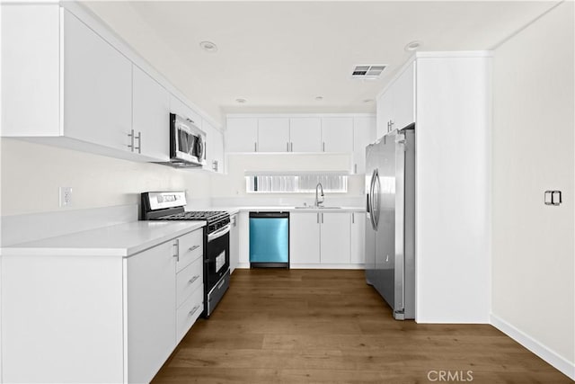 5218 Auckland Ave, Toluca Lake, CA 91601 - kitchen with stainless steel appliances, a sink, dark wood-style flooring, light countertops, and white cabinets