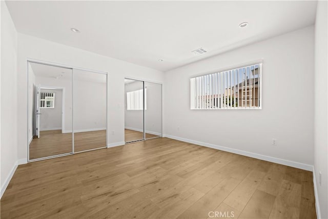 5218 Auckland Ave, Toluca Lake, CA 91601 - unfurnished bedroom with two closets, multiple windows, wood finished floors, and baseboards