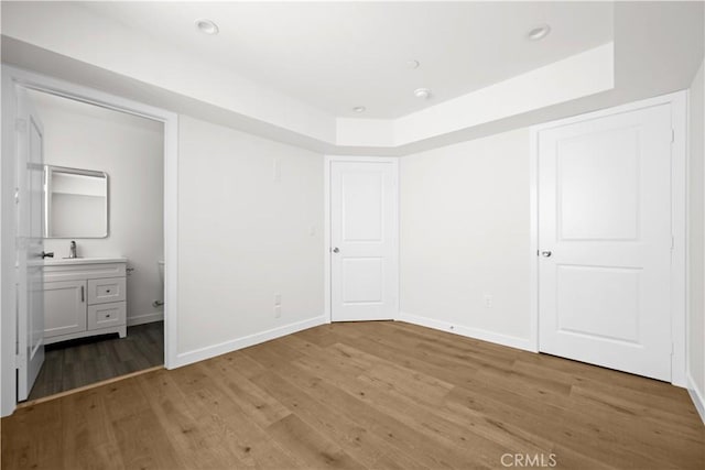 5218 Auckland Ave, Toluca Lake, CA 91601 - unfurnished bedroom featuring light wood-style floors, baseboards, ensuite bathroom, a sink, and a raised ceiling