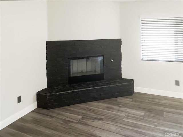 detailed view of a glass covered fireplace, baseboards, and wood finished floors