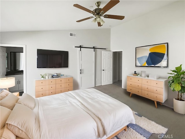 bedroom featuring vaulted ceiling, carpet flooring, a barn door, connected bathroom, and a ceiling fan