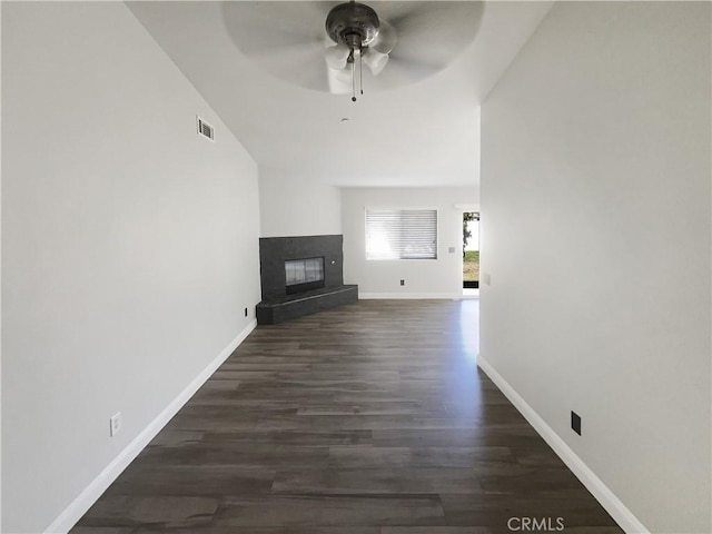 unfurnished living room featuring a ceiling fan, a glass covered fireplace, dark wood finished floors, and baseboards