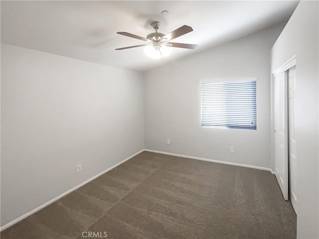 spare room with dark colored carpet, ceiling fan, baseboards, and vaulted ceiling