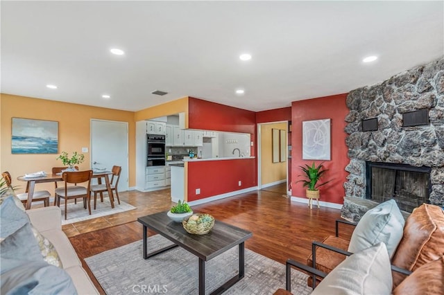 8535 La Vine St, Rancho Cucamonga, CA 91701 - living room featuring a stone fireplace, recessed lighting, wood finished floors, and baseboards