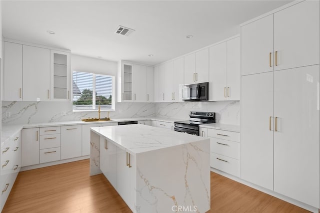 17148 Stare St, Northridge, CA 91325 - kitchen featuring appliances with stainless steel finishes, a sink, light wood-style flooring, a center island, and glass insert cabinets