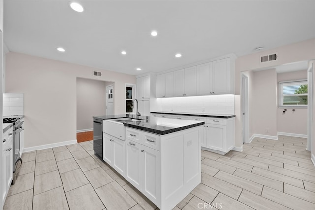 17148 Stare St, Northridge, CA 91325 - kitchen featuring a sink, gas range oven, tasteful backsplash, white cabinets, and a center island with sink