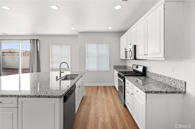 30183 Redding Ave, Murrieta, CA 92563 - kitchen with stainless steel appliances, a sink, baseboards, light wood-style floors, and white cabinetry