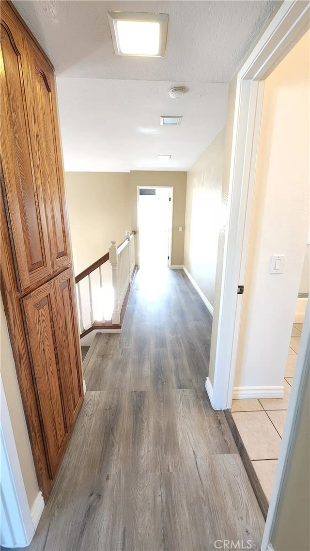 7240 Meadowlark Pl, Rancho Cucamonga, CA 91701 - hallway featuring an upstairs landing, light wood-style floors, baseboards, and a textured ceiling