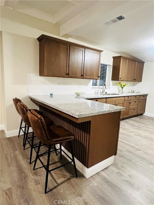 1385 N San Pablo Ave, Fresno, CA 93728 - kitchen with a sink, light wood-style floors, baseboards, a kitchen breakfast bar, and a peninsula
