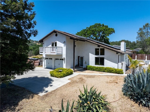 9900 Carmelita Ave, Atascadero, CA 93422 - rear view of property featuring concrete driveway, roof mounted solar panels, a balcony, a chimney, and a garage