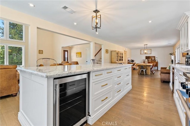 9900 Carmelita Ave, Atascadero, CA 93422 - kitchen with beverage cooler, open floor plan, white cabinets, a kitchen island, and recessed lighting