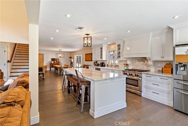 9900 Carmelita Ave, Atascadero, CA 93422 - kitchen featuring appliances with stainless steel finishes, open floor plan, white cabinets, a kitchen bar, and recessed lighting