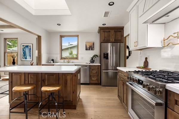 4958 Highland View Ave, Los Angeles, CA 90041 - kitchen with stainless steel appliances, exhaust hood, light countertops, a kitchen island, and light wood finished floors