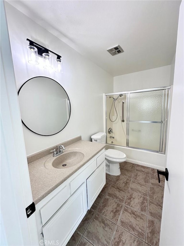 bathroom featuring vanity, toilet, and combined bath / shower with glass door