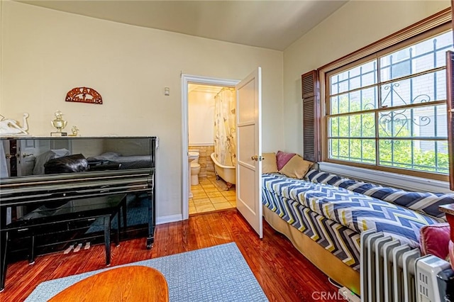 1151 Arapahoe St, Los Angeles, CA 90006 - bedroom featuring radiator, wood finished floors, baseboards, and connected bathroom