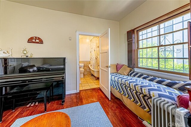 1151 Arapahoe St, Los Angeles, CA 90006 - bedroom featuring radiator heating unit, wood finished floors, baseboards, and ensuite bath