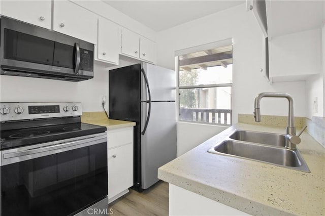 1345 Cabrillo Park Dr Unit J08, Santa Ana, CA 92701 - kitchen featuring appliances with stainless steel finishes, a sink, white cabinetry, light countertops, and light wood finished floors