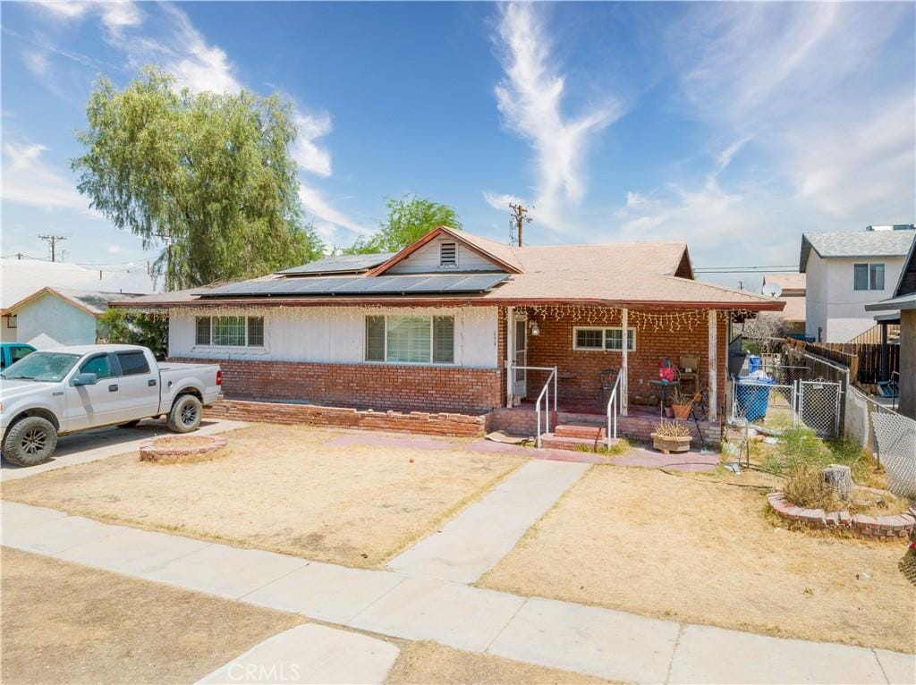 634 W Holt Ave, El Centro, CA 92243 - view of front facade with brick siding, a porch, and solar panels