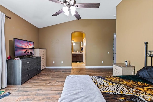 1457 Quiet Ct, Merced, CA 95340 - bedroom with arched walkways, vaulted ceiling, wood finished floors, ensuite bathroom, and baseboards