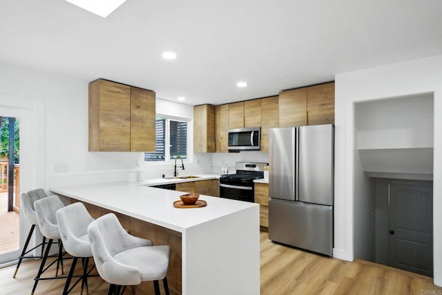 4848 54th St, San Diego, CA 92115 - kitchen featuring appliances with stainless steel finishes, a sink, a peninsula, a breakfast bar area, and light countertops
