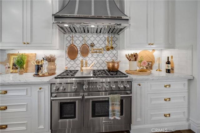 5558 Hoback Glen Rd, Hidden Hills, CA 91302 - kitchen featuring range with two ovens, wall chimney exhaust hood, white cabinets, tasteful backsplash, and light stone counters