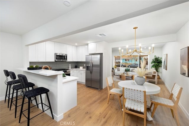 16243 Doublegrove St, La Puente, CA 91744 - kitchen featuring stainless steel appliances, a peninsula, a chandelier, backsplash, and a kitchen breakfast bar