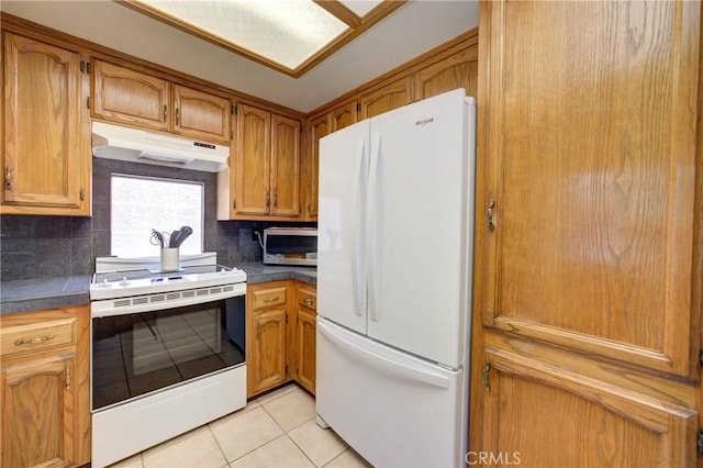 4185 Vanguard Dr, Lompoc, CA 93436 - kitchen featuring white appliances, under cabinet range hood, light tile patterned floors, backsplash, and dark countertops