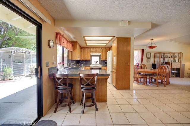 4185 Vanguard Dr, Lompoc, CA 93436 - kitchen featuring a sink, a peninsula, a textured ceiling, brown cabinetry, and light tile patterned floors
