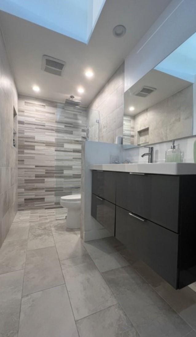 5460 White Oak Ave Unit A305, Encino, CA 91316 - bathroom with tile walls, walk in shower, toilet, vanity, and recessed lighting