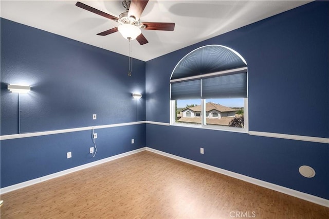 spare room featuring a ceiling fan, baseboards, and wood finished floors