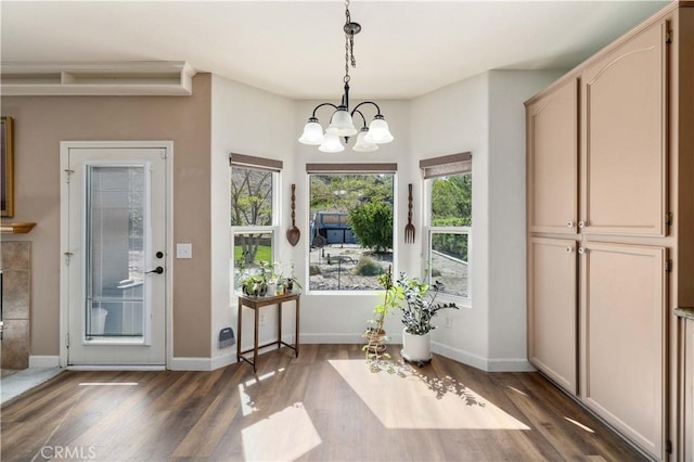 doorway with dark wood-style floors, a chandelier, and baseboards