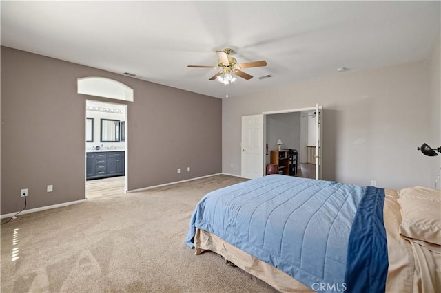 bedroom with light colored carpet, baseboards, ensuite bathroom, and ceiling fan