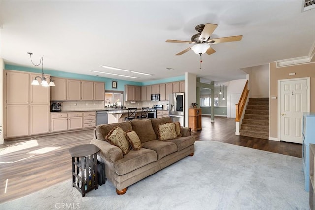 living room with wood finished floors, ceiling fan, stairs, and baseboards