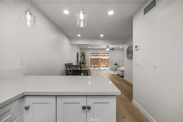1881 Mitchell Ave Unit 114, Tustin, CA 92780 - kitchen featuring a peninsula, white cabinets, light wood finished floors, recessed lighting, and baseboards