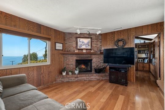 6741 Monero Dr, Rancho Palos Verdes, CA 90275 - living room with wooden walls, light wood-style flooring, track lighting, and a fireplace