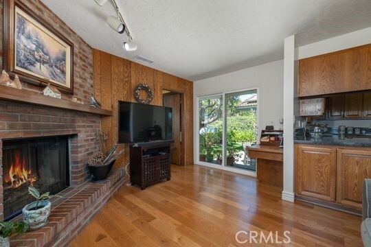 6741 Monero Dr, Rancho Palos Verdes, CA 90275 - living room featuring wooden walls, light wood-style floors, a brick fireplace, and rail lighting